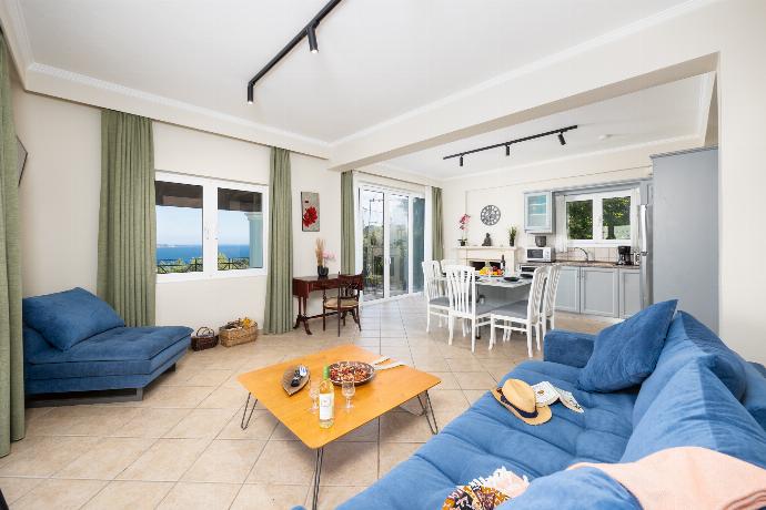 Open-plan living room with sofa, dining area, kitchen, WiFi internet, satellite TV, and sea views . - Villa Eleni Agios Stephanos . (Γκαλερί Φωτογραφιών) }}