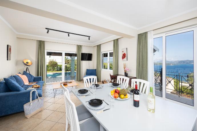 Open-plan living room with sofa, dining area, kitchen, WiFi internet, satellite TV, and sea views . - Villa Eleni Agios Stephanos . (Γκαλερί Φωτογραφιών) }}