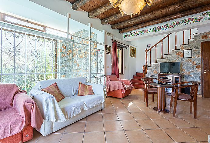 Open-plan living room with sofas, dining area, kitchen, ornamental fireplace, indoor pool, WiFi internet, satellite TV, DVD player, and terrace access . - Villa Tzina . (Galleria fotografica) }}