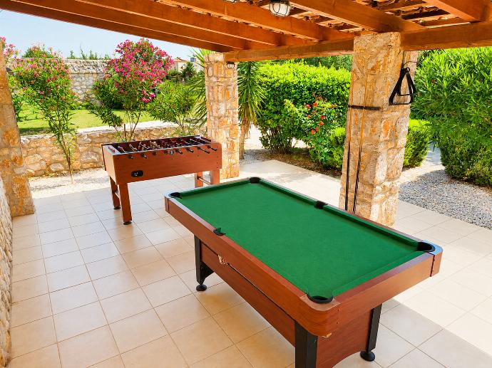 Covered outdoor games area with a pool table, table football, and lush garden surroundings. . - Villa Nineta . (Photo Gallery) }}