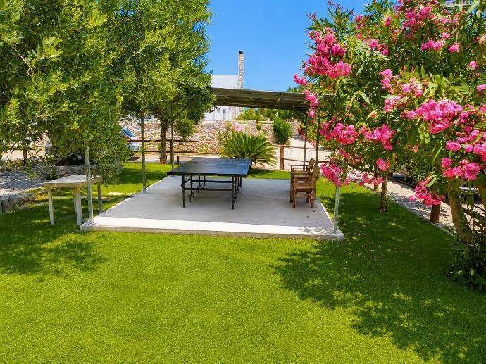 Shaded garden recreation area with a ping pong table, lush greenery, and colorful flowers. . - Villa Nineta . (Photo Gallery) }}
