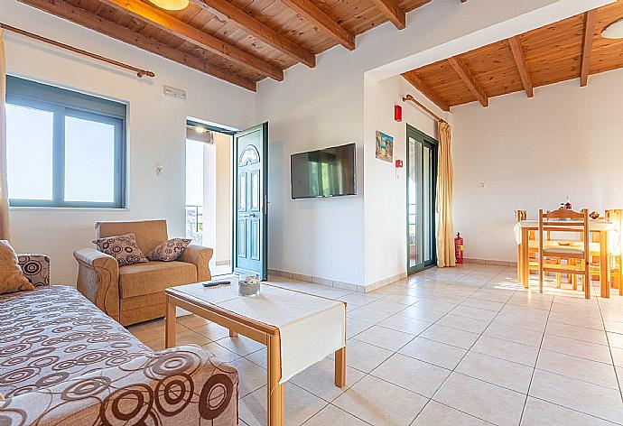 Open-plan living room with sofas, dining area, kitchen, A/C, WiFi internet, satellite TV, DVD player, and terrace access . - Andreas Beach Villa . (Fotogalerie) }}