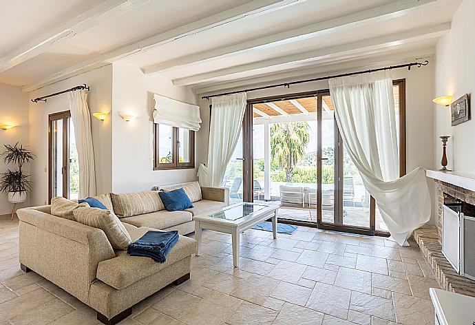 Open-plan living room with sofa, dining area, kitchen, ornamental fireplace, A/C, WiFi internet, satellite TV, and terrace access . - Villa Zacharenia . (Galería de imágenes) }}