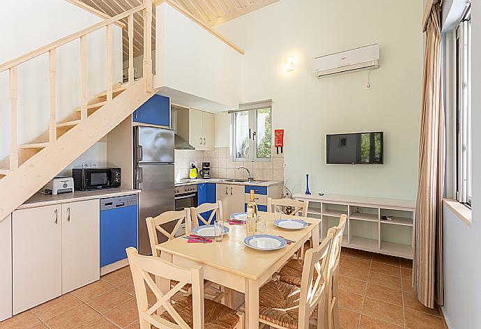 Open-plan living room with sofa, dining area, kitchen, mezzanine, A/C, WiFi internet, satellite TV, and terrace access . - Nafsika Beach House . (Fotogalerie) }}