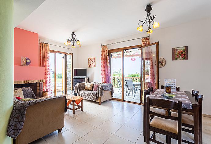 Open-plan living room with sofas, dining area, kitchen, ornamental fireplace, A/C, WiFi internet, satellite TV, DVD player, and terrace access . - Villa Garifallia . (Galleria fotografica) }}