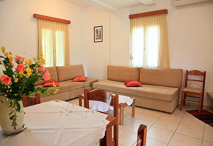 Open-plan living room with sofas, dining area, kitchen, ornamental fireplace, A/C, WiFi internet, and DVD player . - Villa Dimitris . (Fotogalerie) }}