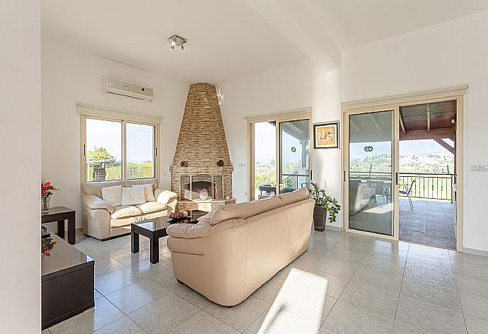 Open-plan living room with sofas, dining area, kitchen, ornamental fireplace, A/C, WiFi internet, satellite TV, DVD player, and terrace access . - Villa Prodromos . (Fotogalerie) }}