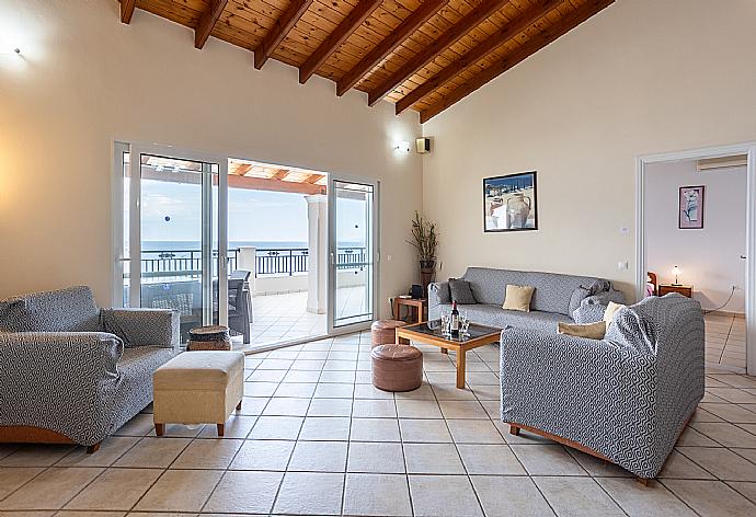 Open-plan living room with sofas, dining area, kitchen, ornamental fireplace, WiFi internet, satellite TV, and sea views . - Villa Kerkyroula . (Fotogalerie) }}