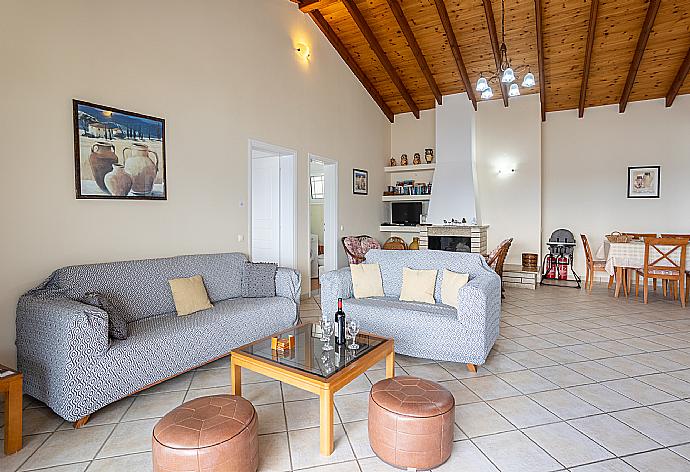 Open-plan living room with sofas, dining area, kitchen, ornamental fireplace, WiFi internet, satellite TV, and sea views . - Villa Kerkyroula . (Fotogalerie) }}