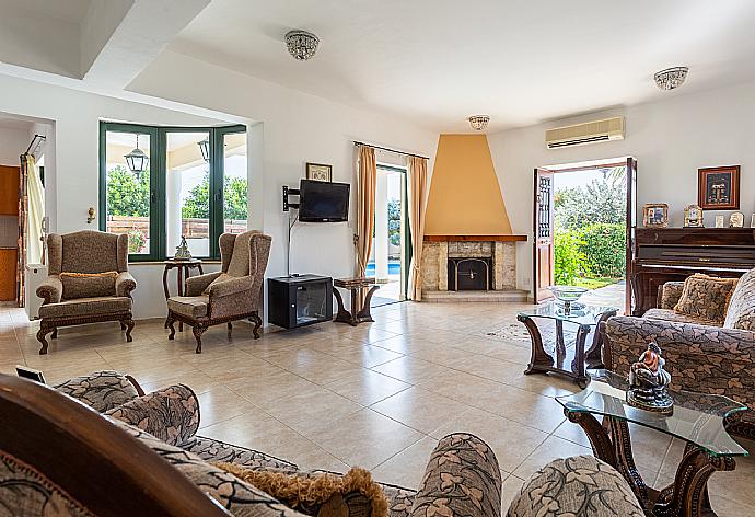 Open-plan living room with sofas, dining area, kitchen, ornamental fireplace, A/C, WiFi internet, satellite TV, and terrace access . - Villa Charianna . (Galleria fotografica) }}