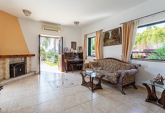 Open-plan living room with sofas, dining area, kitchen, ornamental fireplace, A/C, WiFi internet, satellite TV, and terrace access . - Villa Charianna . (Galería de imágenes) }}