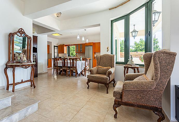 Open-plan living room with sofas, dining area, kitchen, ornamental fireplace, A/C, WiFi internet, satellite TV, and terrace access . - Villa Charianna . (Galleria fotografica) }}