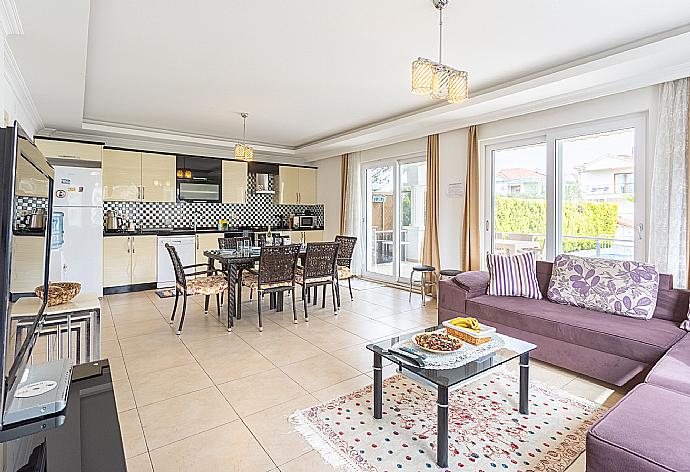 Open-plan living room with sofas, dining area, kitchen, A/C, WiFi internet, satellite TV, and terrace access . - Villa Canberk . (Fotogalerie) }}