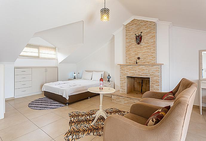 Double bedroom with en suite bathroom, A/C, seating, ornamental fireplace, and balcony access . - Villa Canberk . (Galleria fotografica) }}