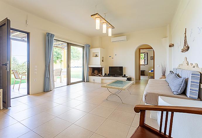 Open-plan living room with sofa, dining area, kitchen, ornamental fireplace, A/C, WiFi internet, satellite TV, DVD player, and terrace access . - Villa Liakada . (Galleria fotografica) }}