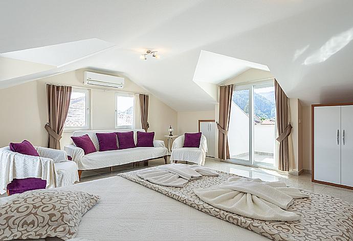 Double bedroom with en suite bathroom, A/C, seating area, and balcony access . - Villa Seda . (Photo Gallery) }}