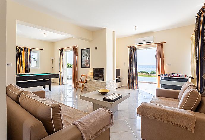 Open-plan living room with sofas, dining area, kitchen, ornamental fireplace, A/C, WiFi internet, satellite TV, pool table, foosball table, and terrace access with sea views . - Kalisto Beach Villa . (Photo Gallery) }}