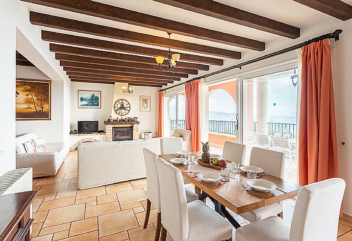 Open-plan living room with sofas, dining areas, kitchen, ornamental fireplace, WiFi internet, satellite TV, and terrace access with panoramic sea views . - Villa Emilios . (Galleria fotografica) }}