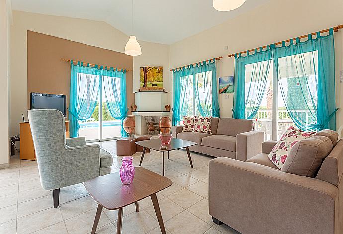 Open-plan living room with sofas, dining area, kitchen, ornamental fireplace, WiFi internet, satellite TV, DVD player, and pool terrace access . - Villa Christia Maris . (Fotogalerie) }}