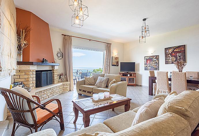 Open-plan living room with sofas, dining area, kitchen, ornamental fireplace, WiFi internet, satellite TV, and balcony access with panoramic sea views . - Villa Vasso . (Photo Gallery) }}
