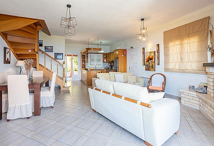 Open-plan living room with sofas, dining area, kitchen, ornamental fireplace, WiFi internet, satellite TV, and balcony access with panoramic sea views . - Villa Vasso . (Photo Gallery) }}