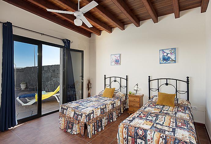 Twin bedroom with ceiling fan and terrace access . - Villa Calma . (Photo Gallery) }}