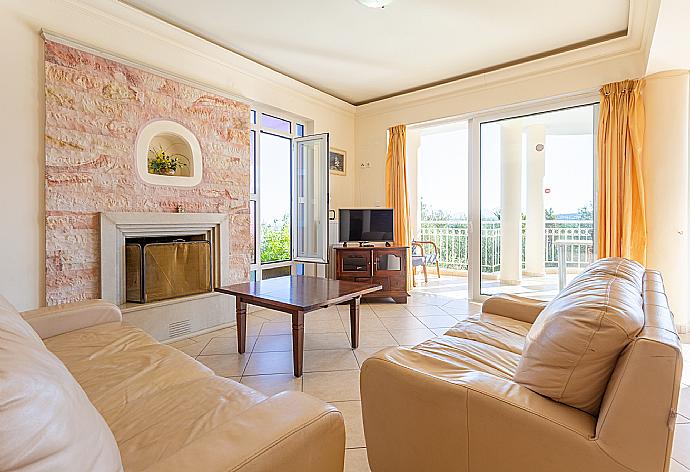 Open-plan living room with sofas, dining area, kitchen, ornamental fireplace, A/C, WiFi internet, satellite TV, DVD player, and balcony access . - Villa Asimenia . (Fotogalerie) }}