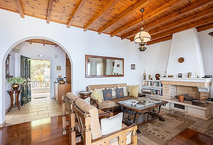 Open-plan living room with sofas, dining area, kitchen, ornamental fireplace, A/C, WiFi internet, satellite TV, and terrace access with sea views . - Villa Elpida . (Fotogalerie) }}