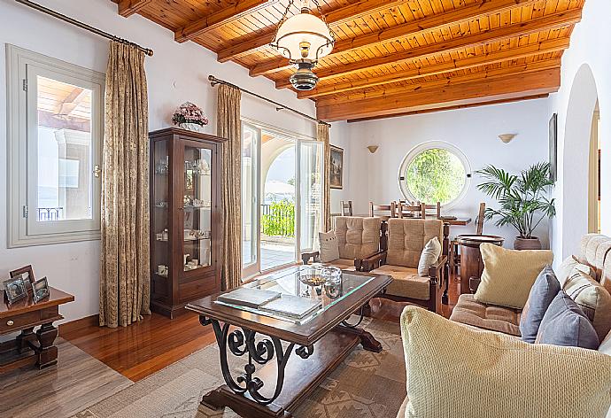 Open-plan living room with sofas, dining area, kitchen, ornamental fireplace, A/C, WiFi internet, satellite TV, and terrace access with sea views . - Villa Elpida . (Fotogalerie) }}