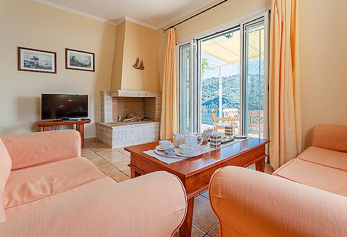 Open-plan living room with sofas, dining area, kitchen, ornamental fireplace, A/C, WiFi internet, satellite TV, and terrace access with panoramic sea views . - Villa Thalassa . (Галерея фотографий) }}