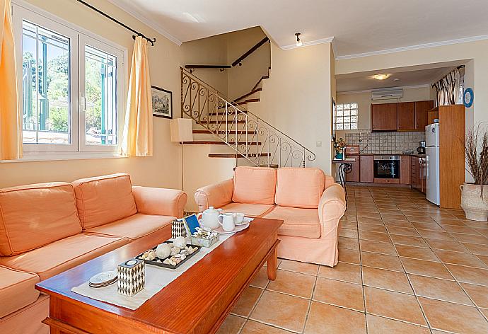 Open-plan living room with sofas, dining area, kitchen, ornamental fireplace, A/C, WiFi internet, satellite TV, and terrace access with panoramic sea views . - Villa Thalassa . (Fotogalerie) }}