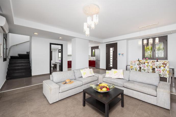 Open-plan living room with sofas, dining area, kitchen, ornamental fireplace, A/C, WiFi internet, satellite TV, and sea views . - Villa Tsampikos . (Galleria fotografica) }}