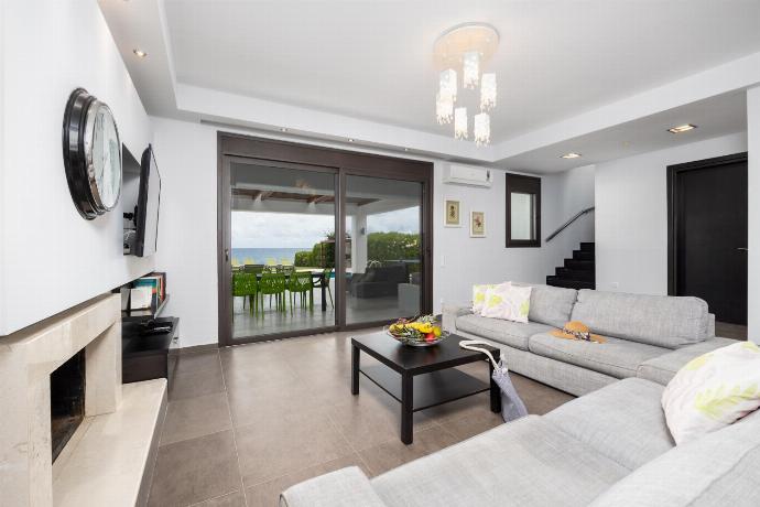 Open-plan living room with sofas, dining area, kitchen, ornamental fireplace, A/C, WiFi internet, satellite TV, and sea views . - Villa Tsampikos . (Galleria fotografica) }}
