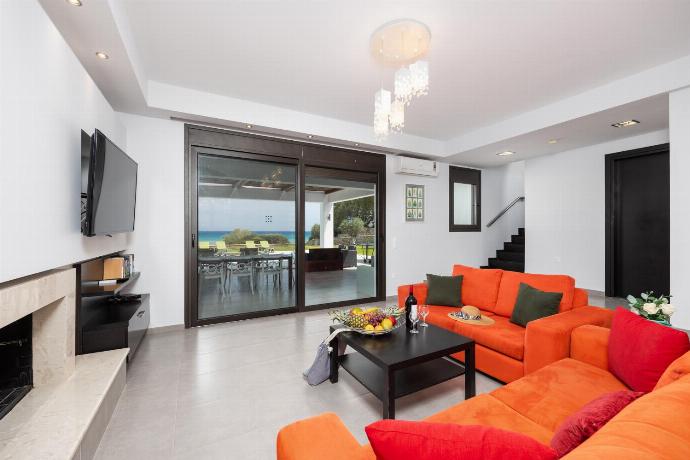 Open-plan living room with sofas, dining area, kitchen, ornamental fireplace, A/C, WiFi internet, satellite TV, and sea views . - Villa Dionysos . (Photo Gallery) }}