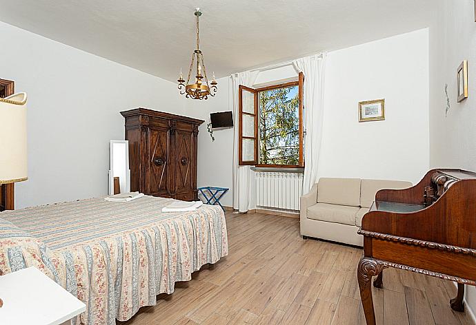 Double bedroom with en suite bathroom, sofa, and TV . - Villa Casa al Sole . (Photo Gallery) }}