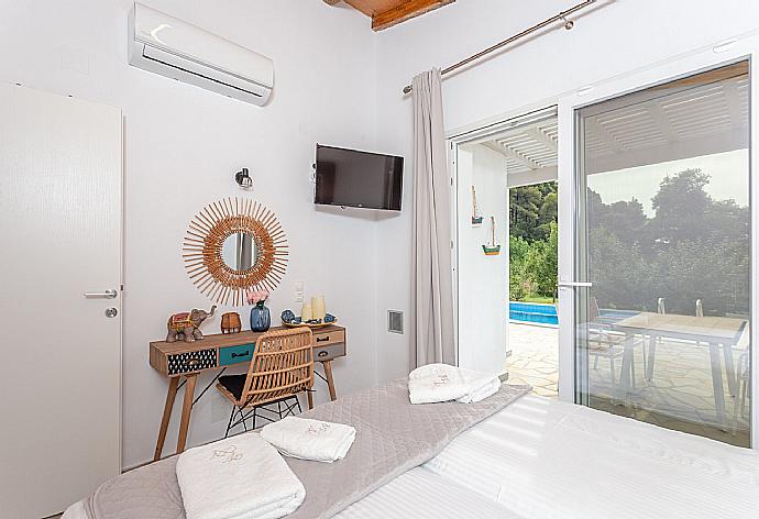 Twin bedroom on ground floor with A/C, TV, and pool terrace access . - Villa Amarandos . (Galería de imágenes) }}