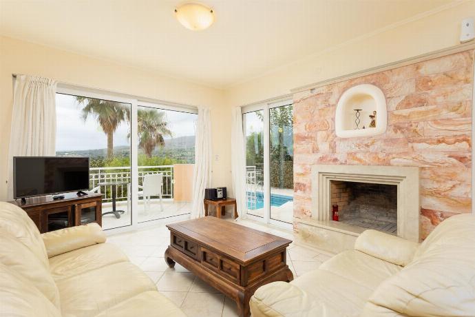 Open-plan living room with sofas, dining area, kitchen, ornamental fireplace, A/C, WiFi internet, and satellite TV . - Villa Callistemon . (Galleria fotografica) }}