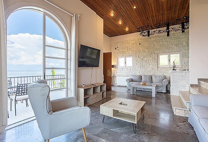 Open-plan living room with sofas, dining area, kitchen, ornamental fireplace, A/C, WiFi internet, satellite TV, and sea views . - Villa Litsa . (Photo Gallery) }}