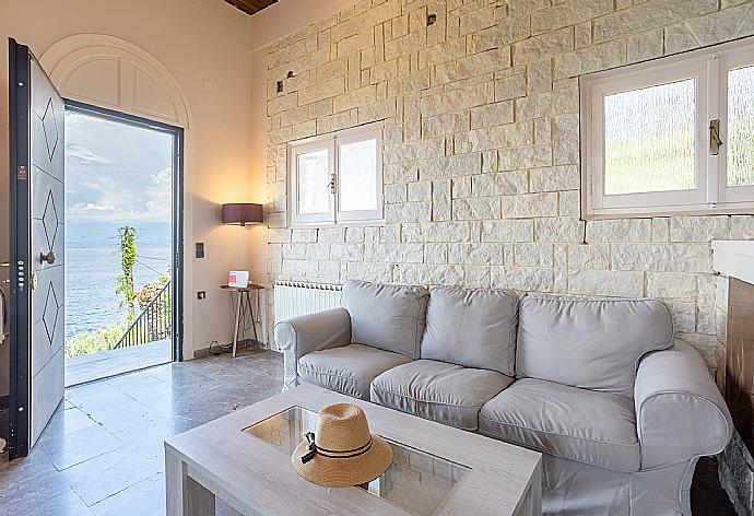 Open-plan living room with sofas, dining area, kitchen, ornamental fireplace, A/C, WiFi internet, satellite TV, and sea views . - Villa Litsa . (Galería de imágenes) }}