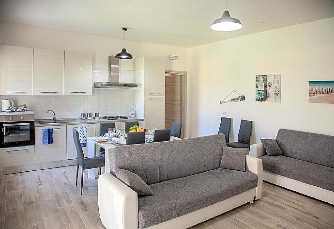 Open-plan living room with sofas, dining area, equipped kitchen, WiFi internet, satellite TV, DVD player, and terrace access . - Villa Villino Blu . (Fotogalerie) }}