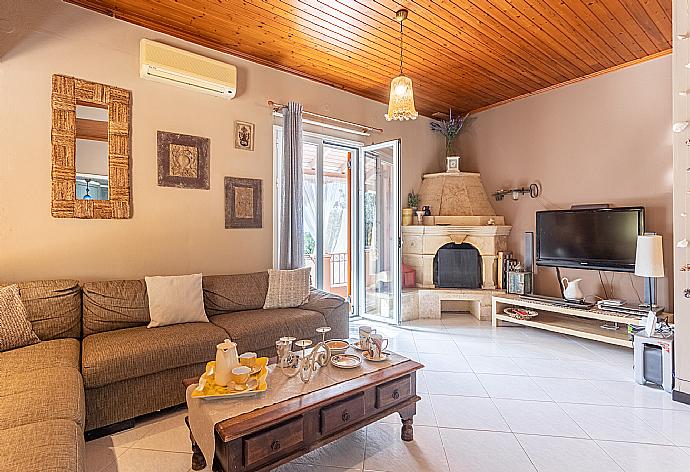 Open-plan living room with sofas, dining area, kitchen, ornamental fireplace, A/C, WiFi internet, and satellite TV . - Dimitris Cottage . (Fotogalerie) }}