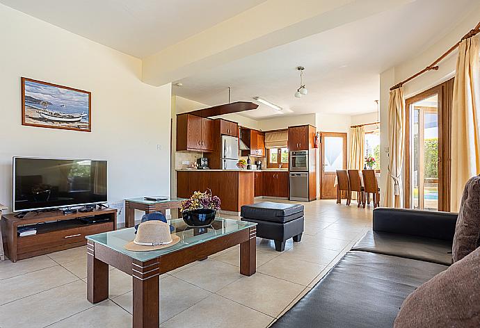 Open-plan living room with sofas, dining area, kitchen, ornamental fireplace, A/C, WiFi internet, and satellite TV . - Villa Tsikkos Tessera . (Photo Gallery) }}