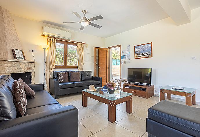 Open-plan living room with sofas, dining area, kitchen, ornamental fireplace, A/C, WiFi internet, and satellite TV . - Villa Tsikkos Tessera . (Fotogalerie) }}