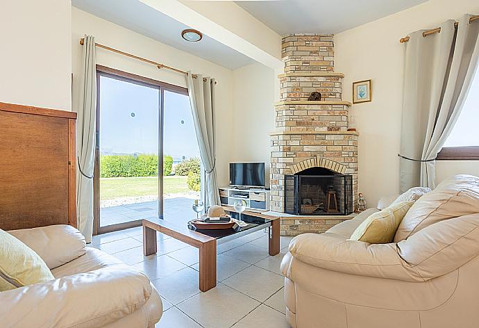 Open-plan living room with sofas, dining area, kitchen, ornamental fireplace, A/C, WiFi internet, satellite TV, and sea views . - Blue Bay Villa Nicole . (Fotogalerie) }}