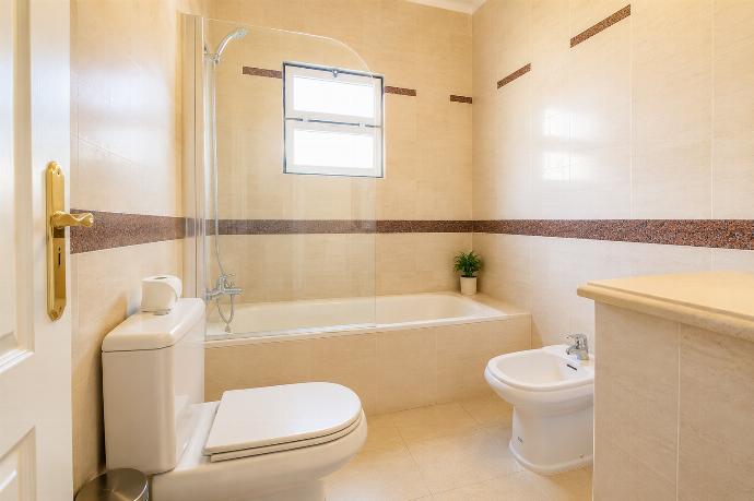 Tiled bathroom featuring a combination bathtub and shower with a glass splash panel, toilet, and bidet. . - Villa Green Palms . (Photo Gallery) }}