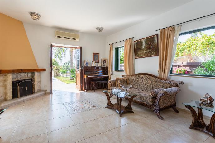 Open-plan living room with sofas, dining area, kitchen, ornamental fireplace, A/C, WiFi internet, satellite TV, and terrace access . - Androula Villas Collection . (Galerie de photos) }}