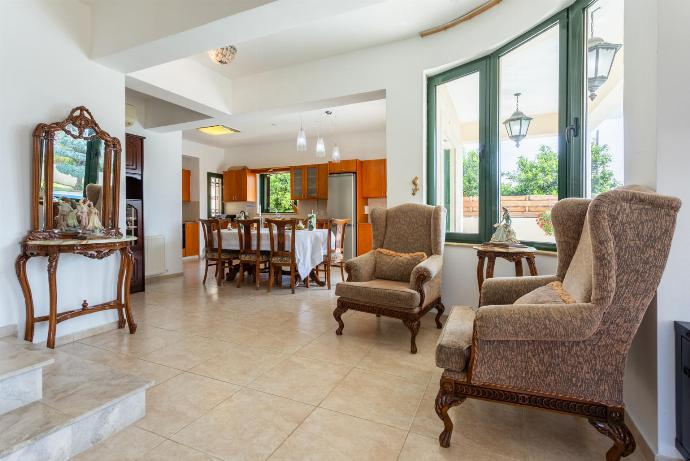 Open-plan living room with sofas, dining area, kitchen, ornamental fireplace, A/C, WiFi internet, satellite TV, and terrace access . - Androula Villas Collection . (Galerie de photos) }}