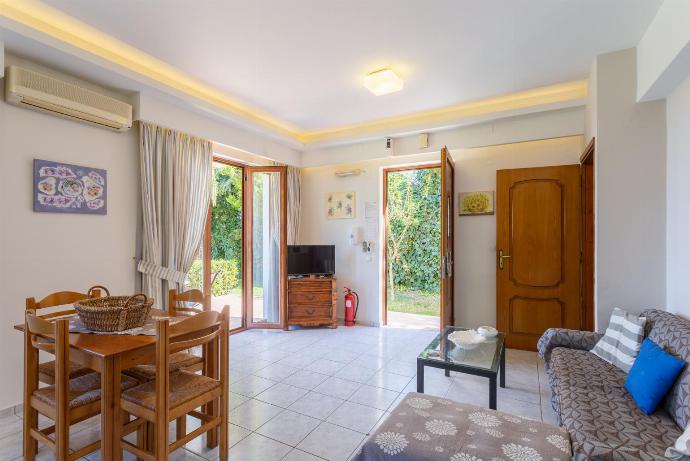 Open-plan living room with sofa, dining area, kitchen, A/C, WiFi internet and satellite TV, and terrace access . - Maroulas Villas Collection . (Galleria fotografica) }}