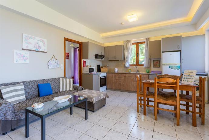 Open-plan living room with sofa, dining area, kitchen, A/C, WiFi internet and satellite TV, and terrace access . - Maroulas Villas Collection . (Galleria fotografica) }}