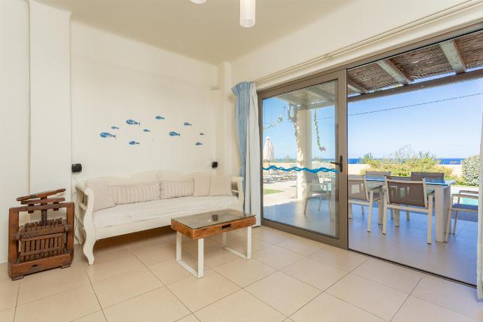 Open-plan living room with sofa, dining area, kitchen, ornamental fireplace, A/C, WiFi internet, satellite TV, and terrace access . - Panormos Villas Collection . (Galleria fotografica) }}